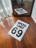 Speed limit street sign with 'SPEED LIMIT 69' on a wooden floor.